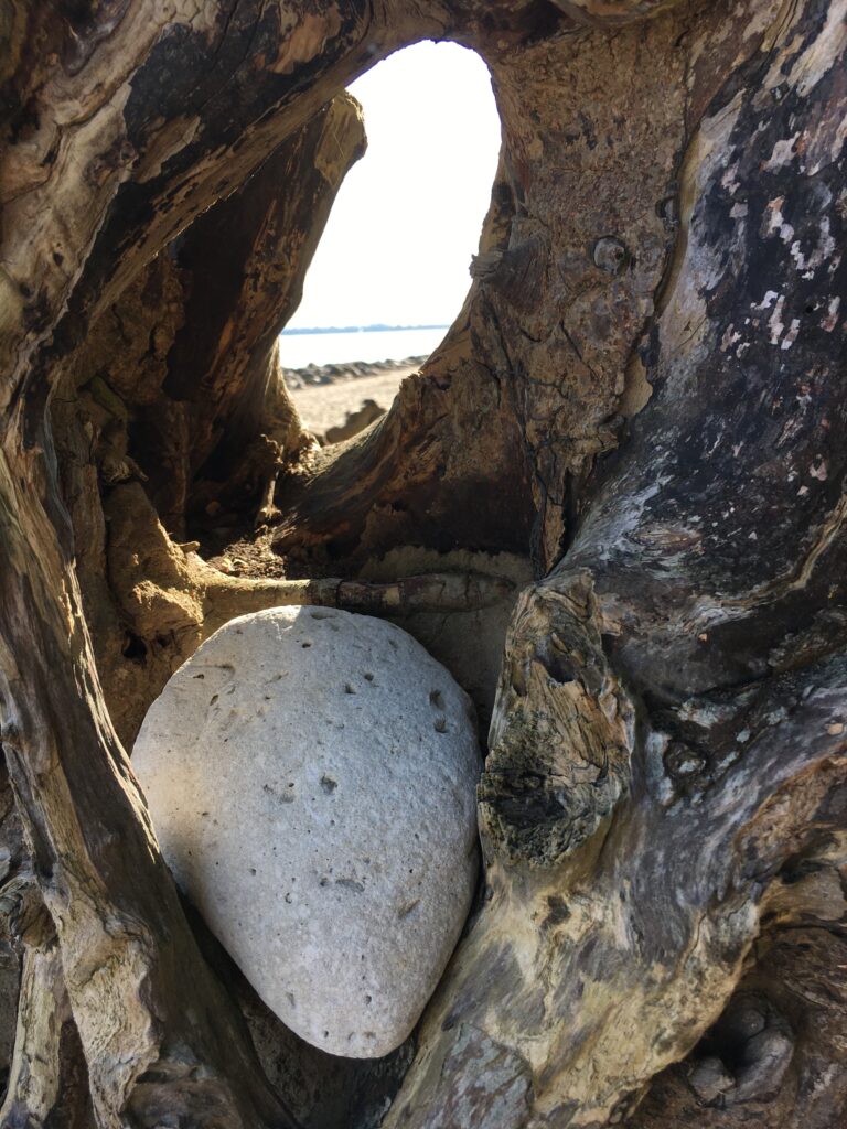 Heller Stein zwischen verwittertem Holz mit Blick zum Meer